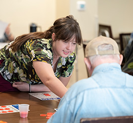 resident assistant helping man play bingo